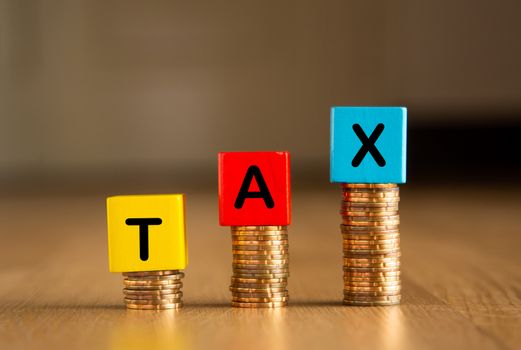 Tax Conceptual image: Wooden blocks and coins arranged with the words TAX