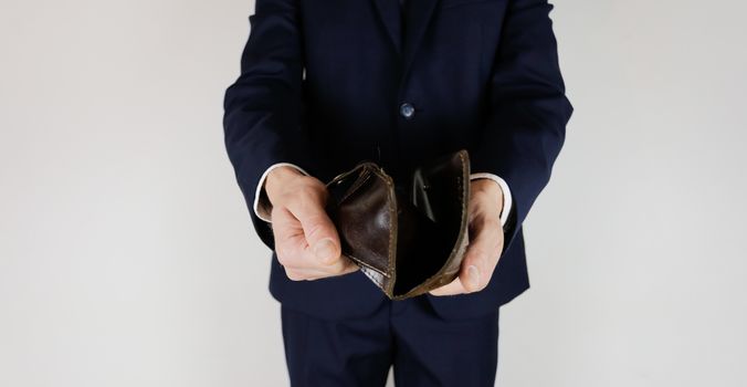 A man in a business suit holds in his hands an empty wallet without money. Financial crisis. Bankruptcy in business. The employer is disappointed.