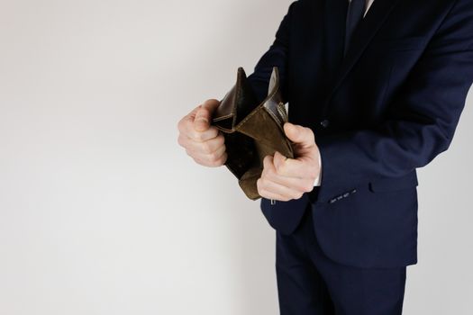 A man in a business suit holds in his hands an empty wallet without money. Financial crisis. Bankruptcy in business. The employer is disappointed.