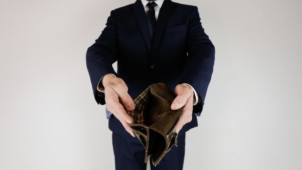 A man in a business suit holds in his hands an empty wallet without money. Financial crisis. Bankruptcy in business. The employer is disappointed.