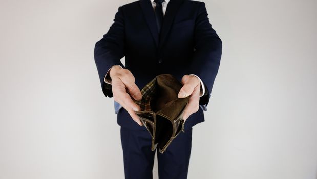 A man in a business suit holds in his hands an empty wallet without money. Financial crisis. Bankruptcy in business. The employer is disappointed.