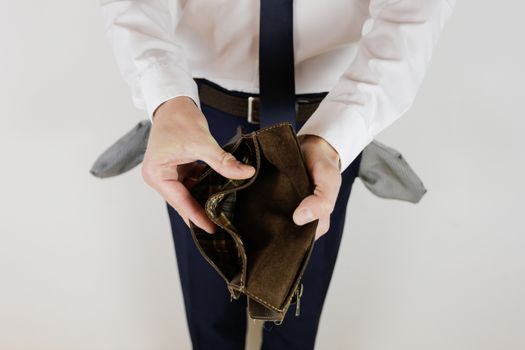 A man in a business suit holds in his hands an empty wallet without money. Financial crisis. Bankruptcy in business. The employer is disappointed.