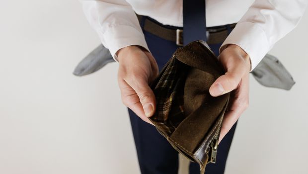 A man in a business suit holds in his hands an empty wallet without money. Financial crisis. Bankruptcy in business. The employer is disappointed.