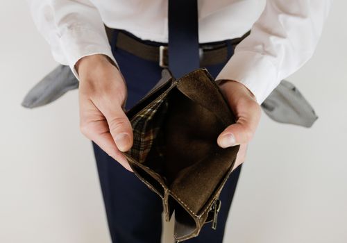 A man in a business suit holds in his hands an empty wallet without money. Financial crisis. Bankruptcy in business. The employer is disappointed.