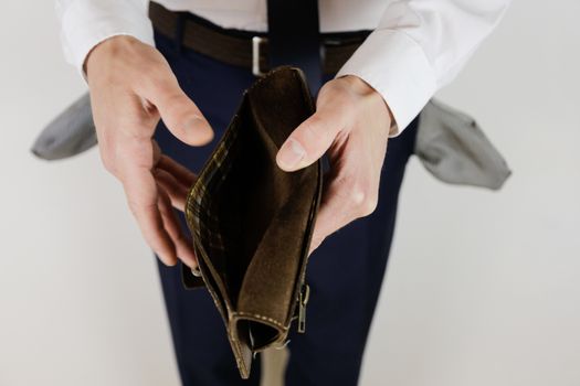 A man in a business suit holds in his hands an empty wallet without money. Financial crisis. Bankruptcy in business. The employer is disappointed.