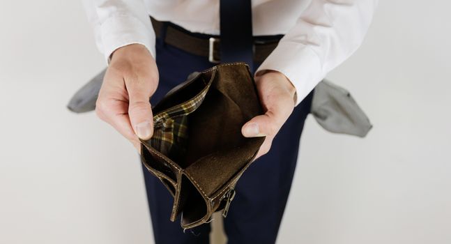 A man in a business suit holds in his hands an empty wallet without money. Financial crisis. Bankruptcy in business. The employer is disappointed.