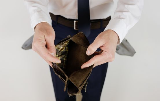 A man in a business suit holds in his hands an empty wallet without money. Financial crisis. Bankruptcy in business. The employer is disappointed.