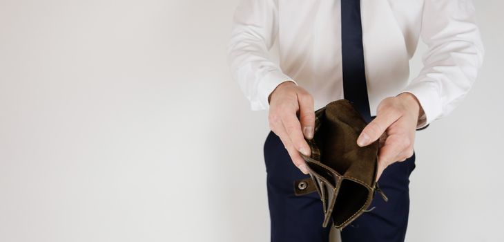 A man in a business suit holds in his hands an empty wallet without money. Financial crisis. Bankruptcy in business. The employer is disappointed.