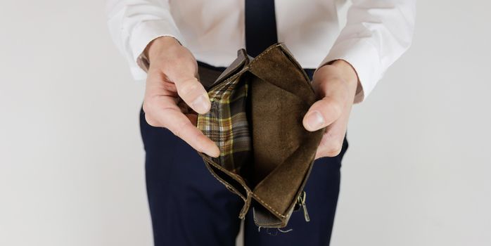 A man in a business suit holds in his hands an empty wallet without money. Financial crisis. Bankruptcy in business. The employer is disappointed.