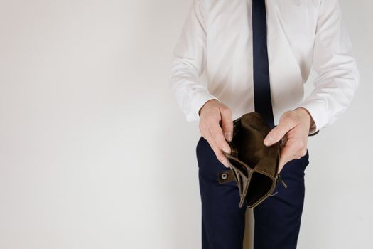 A man in a business suit holds in his hands an empty wallet without money. Financial crisis. Bankruptcy in business. The employer is disappointed.