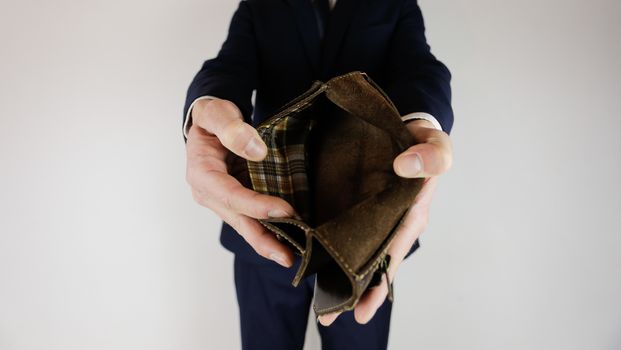 A man in a business suit holds in his hands an empty wallet without money. Financial crisis. Bankruptcy in business. The employer is disappointed.