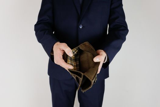 A man in a business suit holds in his hands an empty wallet without money. Financial crisis. Bankruptcy in business. The employer is disappointed.