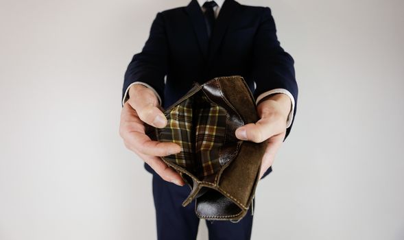 A man in a business suit holds in his hands an empty wallet without money. Financial crisis. Bankruptcy in business. The employer is disappointed.