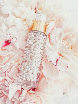 Luxurious cosmetic bottle as antiaging skincare product on background of flowers, blank label packaging for body care branding design