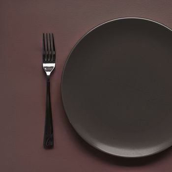 Empty plate and cutlery as mockup set on dark brown background, top tableware for chef table decor and menu branding design