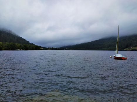 Dramatic scene of a boat on the lake in Gerardmer, France on a cloudy and stormy day
