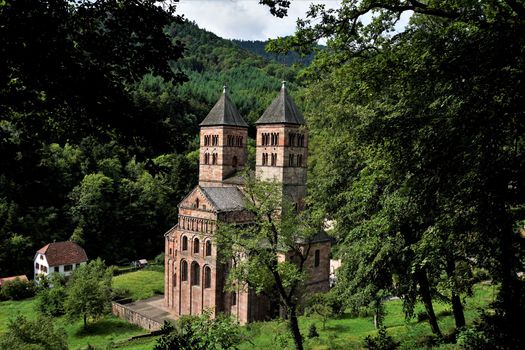 Murbach Abbey hidden behind trees with town hall of Murbach, France