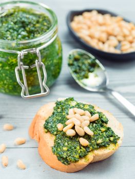 Close up view of baguette bread with fresh basil pesto sauce on gray wooden table. Copy space.