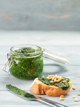 Close up view of baguette bread with fresh basil pesto sauce on gray wooden table. Copy space.