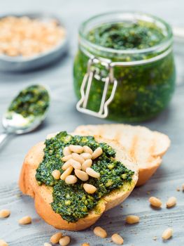 Close up view of baguette bread with fresh basil pesto sauce on gray wooden table. Copy space.