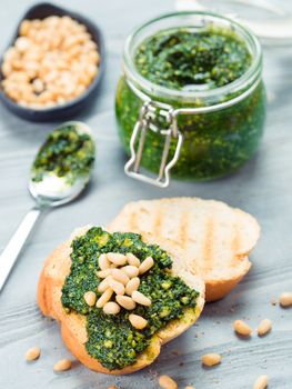 Close up view of baguette bread with fresh basil pesto sauce on gray wooden table. Copy space.