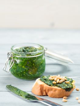 Close up view of baguette bread with fresh basil pesto sauce on gray wooden table. Copy space.