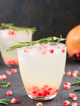 Autumn and winter cocktails idea - white sangria with rosemary, pomegrante and lemon juice and ingredients on black cement background.