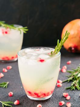 Autumn and winter cocktails idea - white sangria with rosemary, pomegrante and lemon juice and ingredients on black cement background.