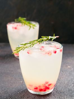 Autumn and winter cocktails idea - white sangria with rosemary, pomegrante and lemon juice on black cement background.