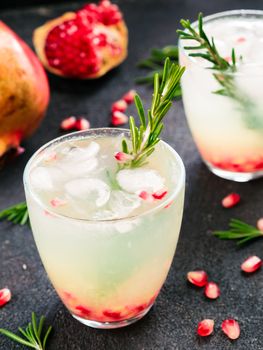 Autumn and winter cocktails idea - white sangria with rosemary, pomegrante and lemon juice and ingredients on black cement background.