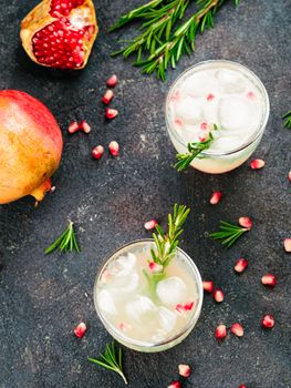 Autumn and winter cocktails idea - white sangria with rosemary, pomegrante and lemon juice and ingredients on black cement background. Copy space. Top view or flat-lay.