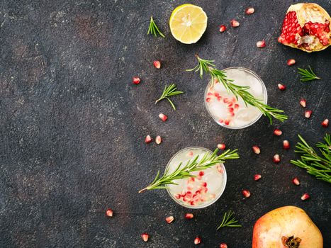 Autumn and winter cocktails idea - white sangria with rosemary, pomegrante and lemon juice and ingredients on black cement background. Copy space. Top view or flat-lay.