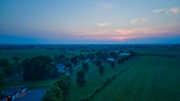 Aerial view of a summer sunset over farm lands with blue skies and red sun