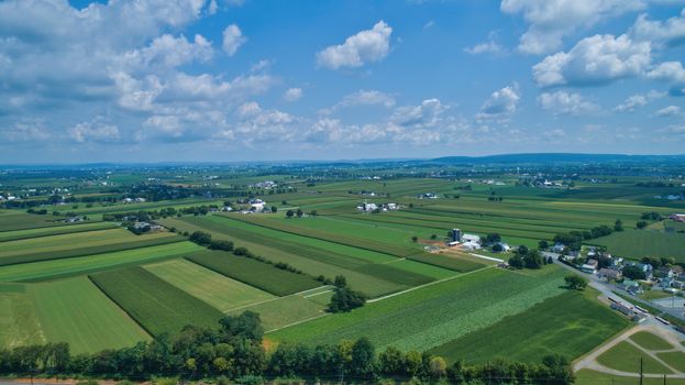 Aerial view of farm lands in summer with blue skies and white fluffy clouds