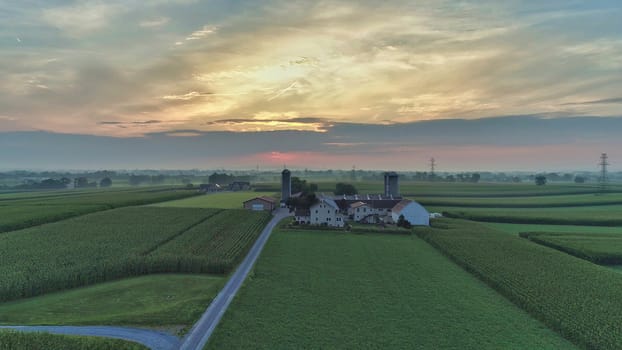 Aerial view of a summer sunset over farm lands with blue skies and red sun