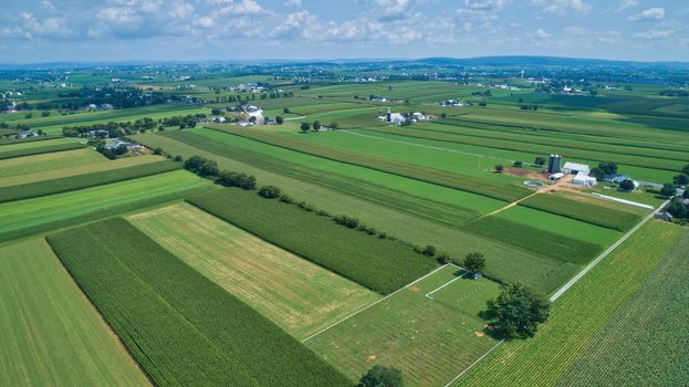 Aerial view of farm lands in summer with blue skies and white fluffy clouds