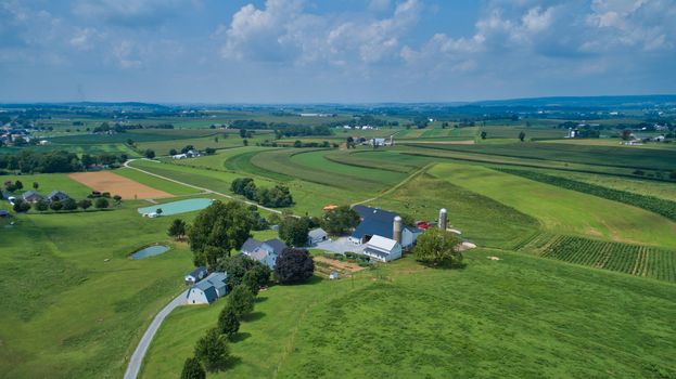 Aerial view of green farmlands and rolling crops growing on a beautiful sky on a sunny countryside