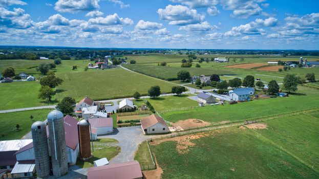 Aerial view of Amish countryside with barns and silos and a one room school house on a sunny summer day