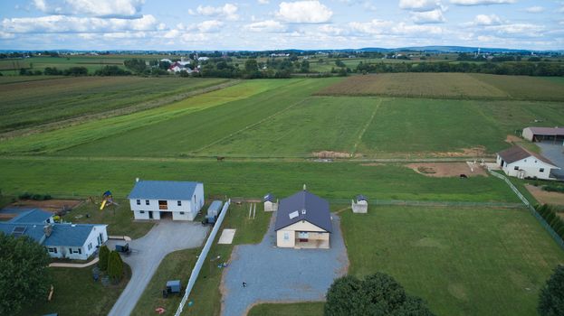 Aerial view of Amish countryside with barns and silos and a one room school house on a sunny summer day