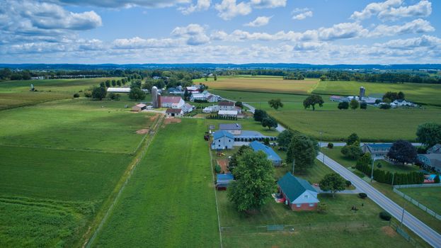 Aerial view of Amish countryside with barns and silos and a one room school house on a sunny summer day