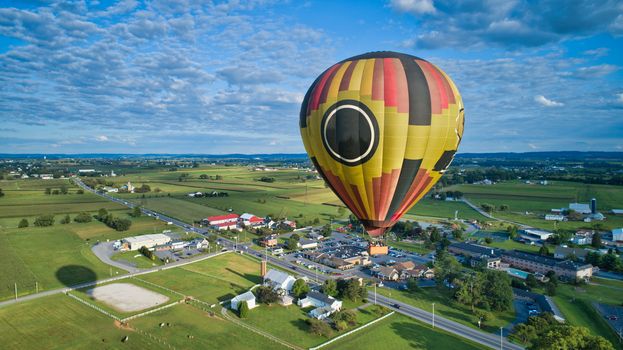 Aerial view of blue sky and multiple clouds and a hot air balloon floating thru it