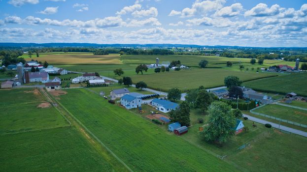 Aerial view of Amish countryside with barns and silos and a one room school house on a sunny summer day