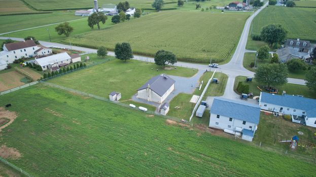 Aerial view of Amish countryside with barns and silos and a one room school house on a sunny summer day