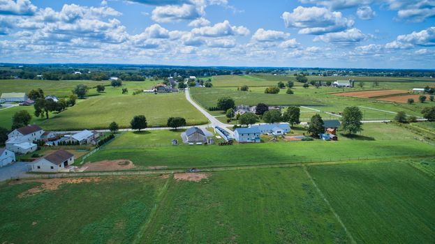 Aerial view of Amish countryside with barns and silos and a one room school house on a sunny summer day