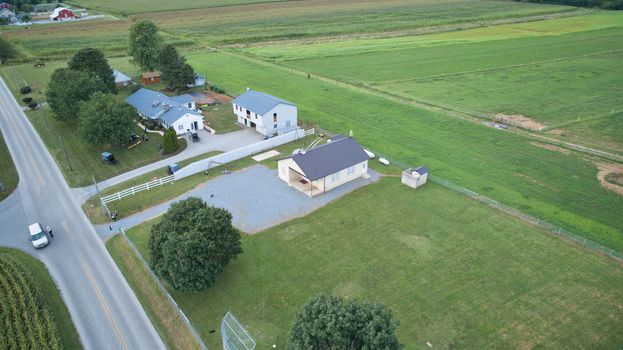 Aerial view of Amish countryside with barns and silos and a one room school house on a sunny summer day