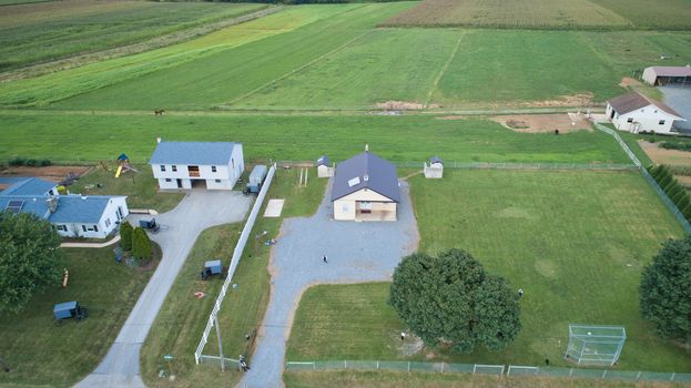 Aerial view of Amish countryside with barns and silos and a one room school house on a sunny summer day