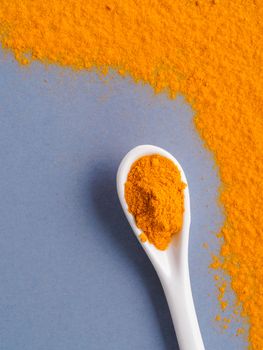 Turmeric Powder or Curcuma longa and white spoon with turmeric powder on gray background. Top view. Copy space for text.