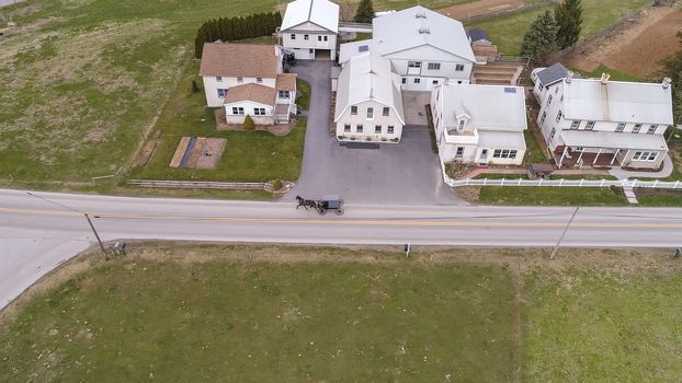 Aerial of an Amish horse and buggy riding on a road on a spring day