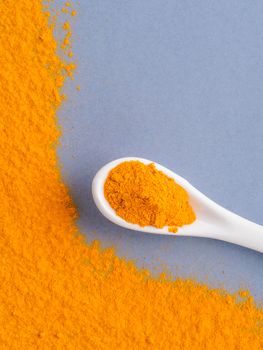 Turmeric Powder or Curcuma longa and white spoon with turmeric powder on gray background. Top view. Copy space for text.