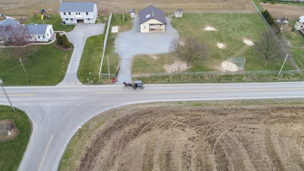 Aerial of an Amish horse and buggy riding on a road on a spring day